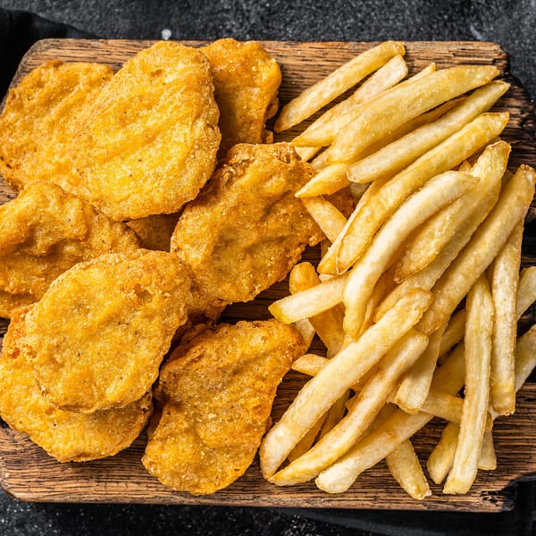 Golden chicken nuggets and crispy french fries on a wooden board, ready to be served at Max Bar & Grill.