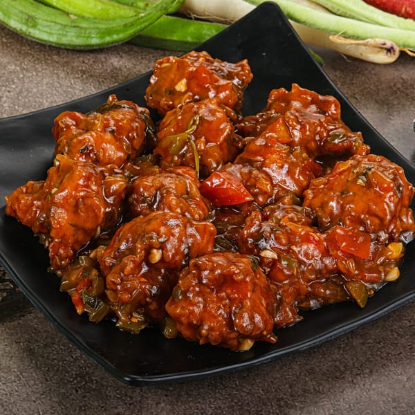 Max Bar & Grill's chicken Manchurian, a popular bar-and-grill dish, served on a black plate.