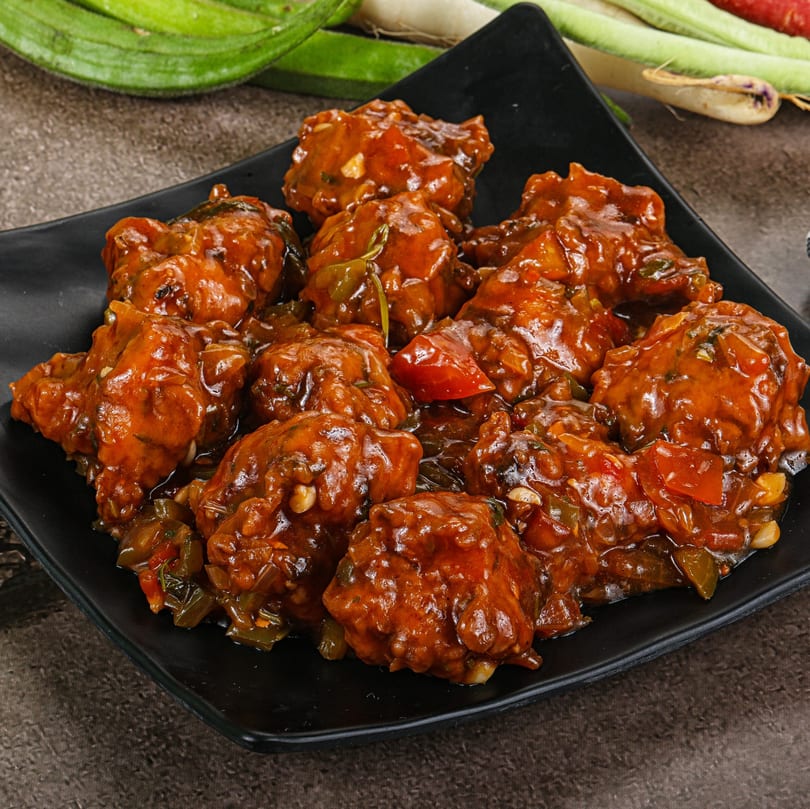 Max Bar & Grill's chicken Manchurian, a popular bar-and-grill dish, served on a black plate.